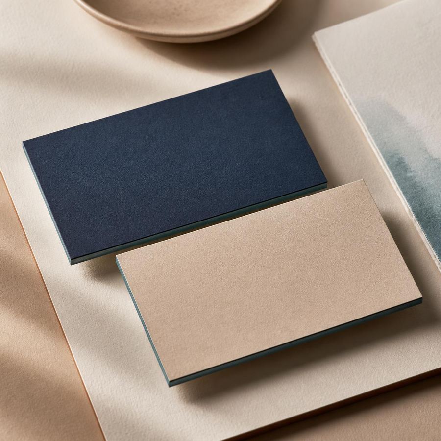 Finished business cards in deep navy and warm sand, printed on textured stock.